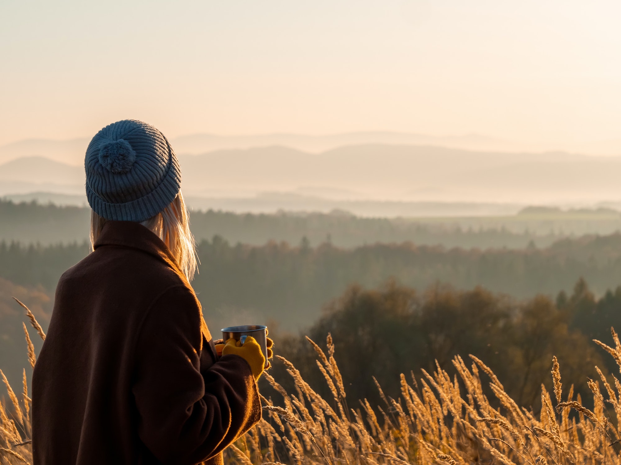 Beautiful girl with mug of tea in mountains Beskides in November in sunset